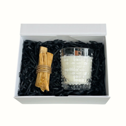 Candle and wooden logs in a decorative box with black shredded paper